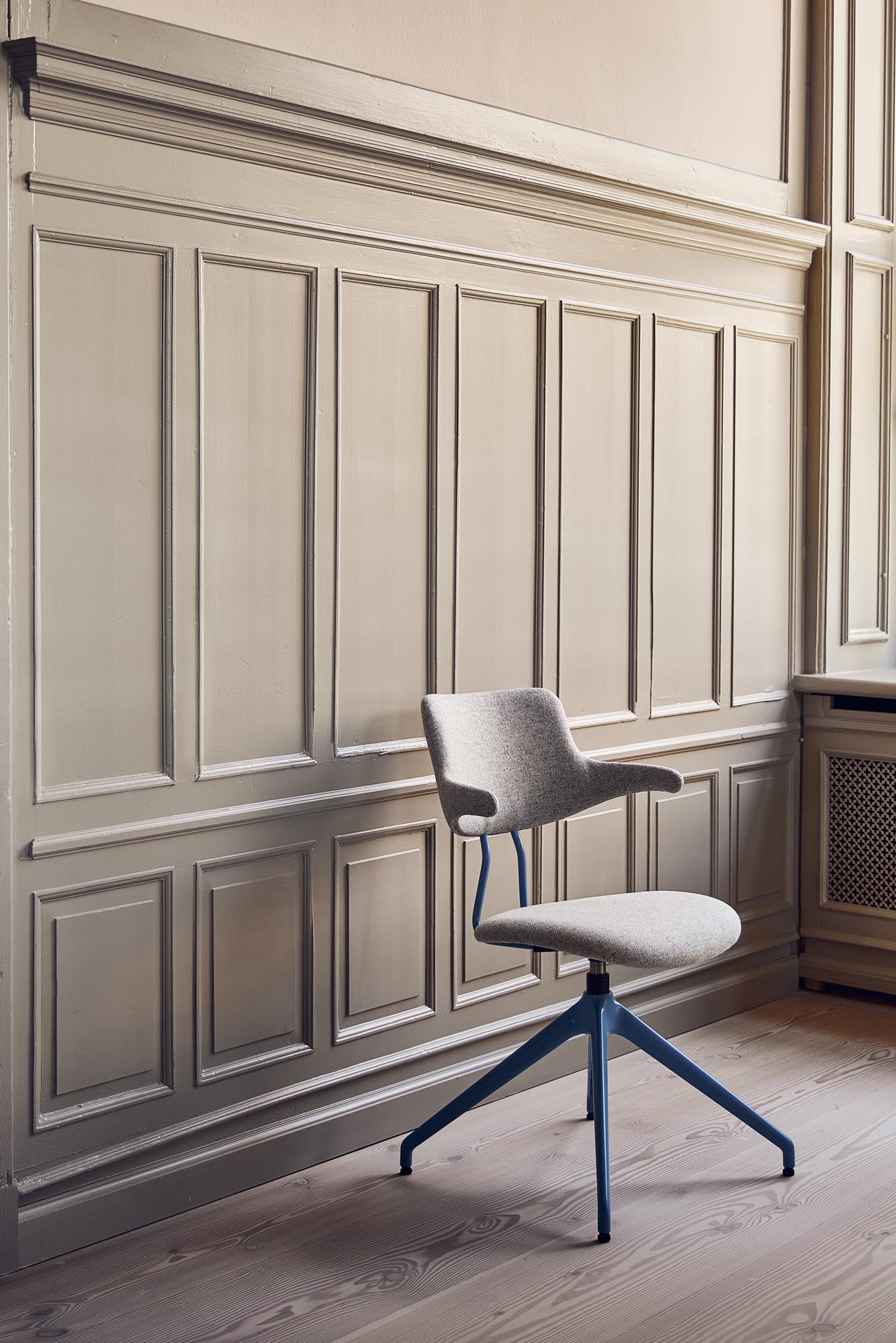 En kontorstol uden hjul fra VERMUND i et minimalistisk kontormiljø med fokus på stilrent design.